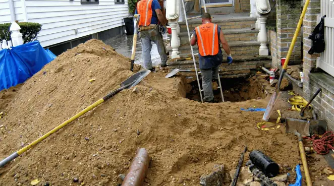 Contractors performing foundation protection and exterior drainage excavation near residential home steps in Green Bay, WI
